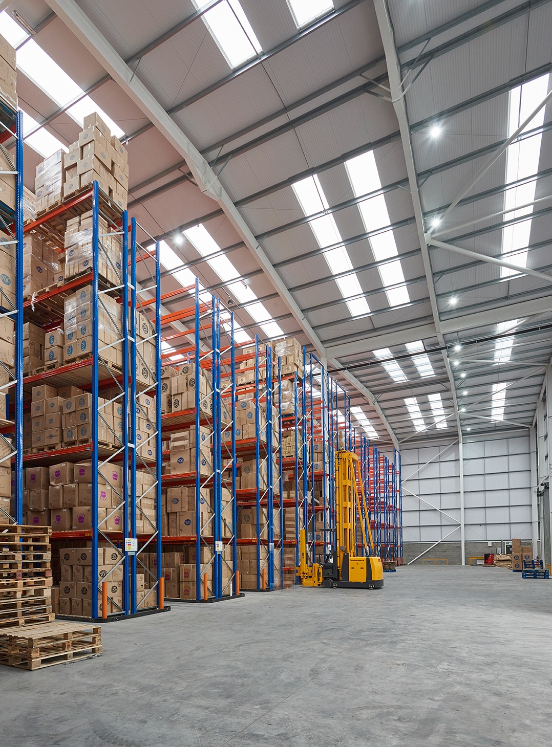 Specialist high-bay forklift operating between warehouse racking aisles
